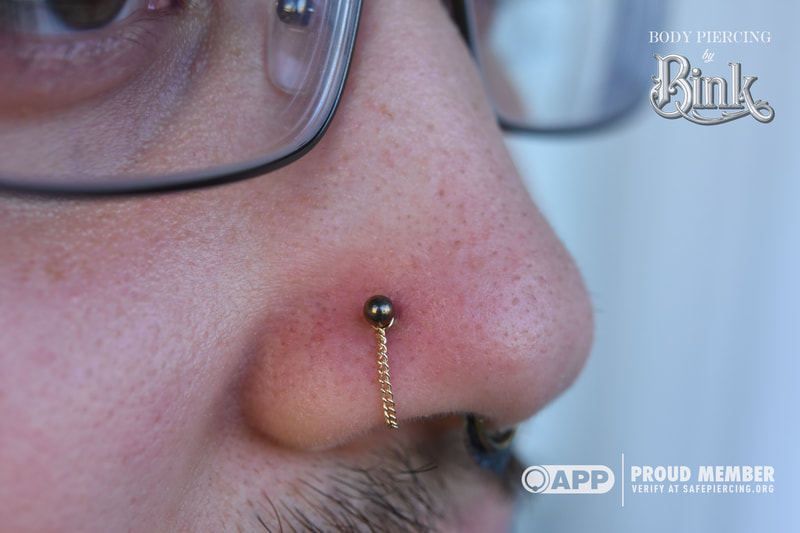 anodized ball end with yellow gold curb chain in healed nostril piercing